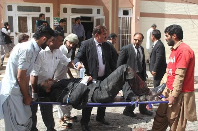 First responders and volunteers transport an injured man away from the scene of a bomb blast outside a hospital in Quetta